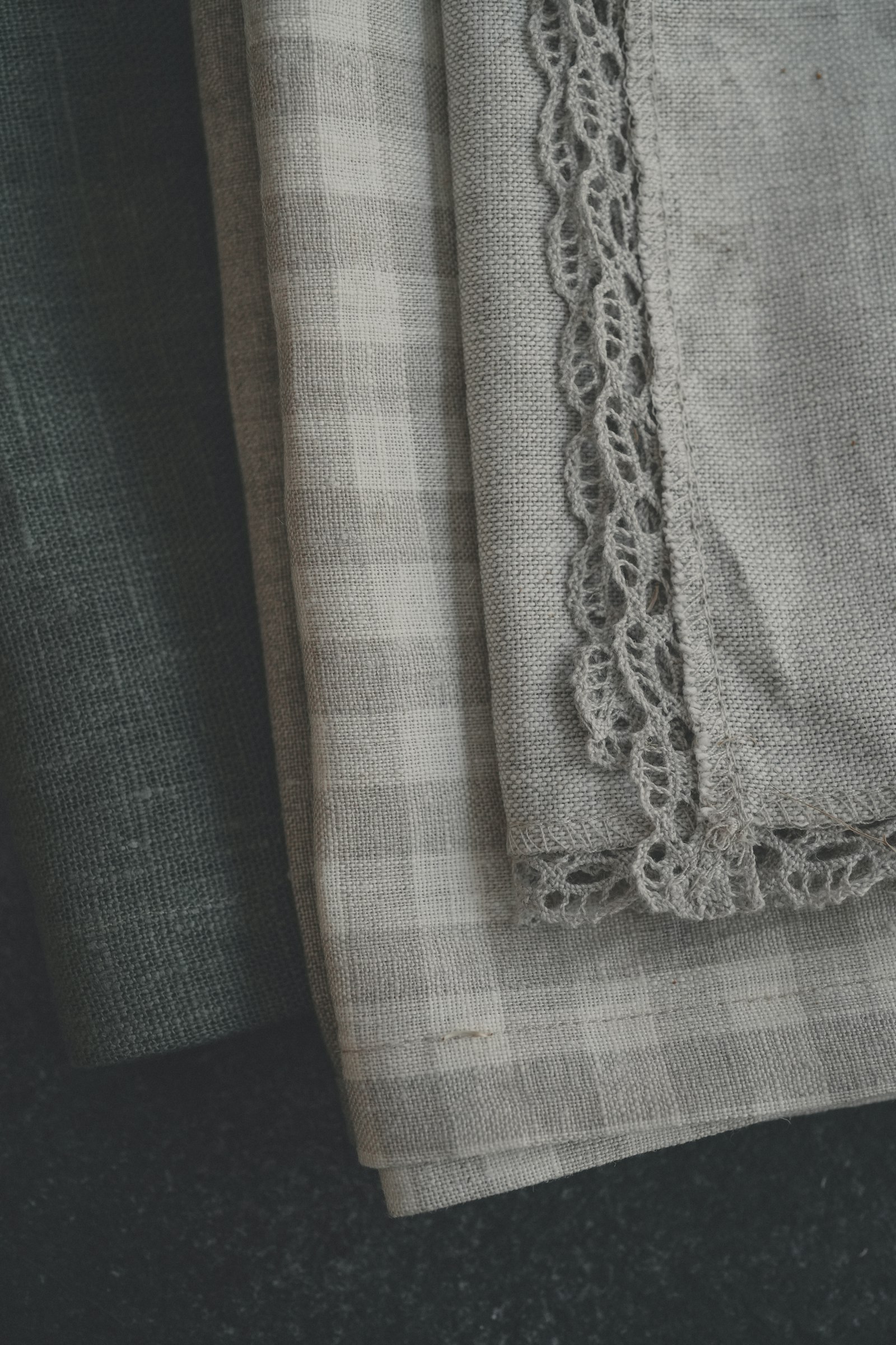 Stack of oat and grey linen napkins with lace-trim edge — table linen and accessories