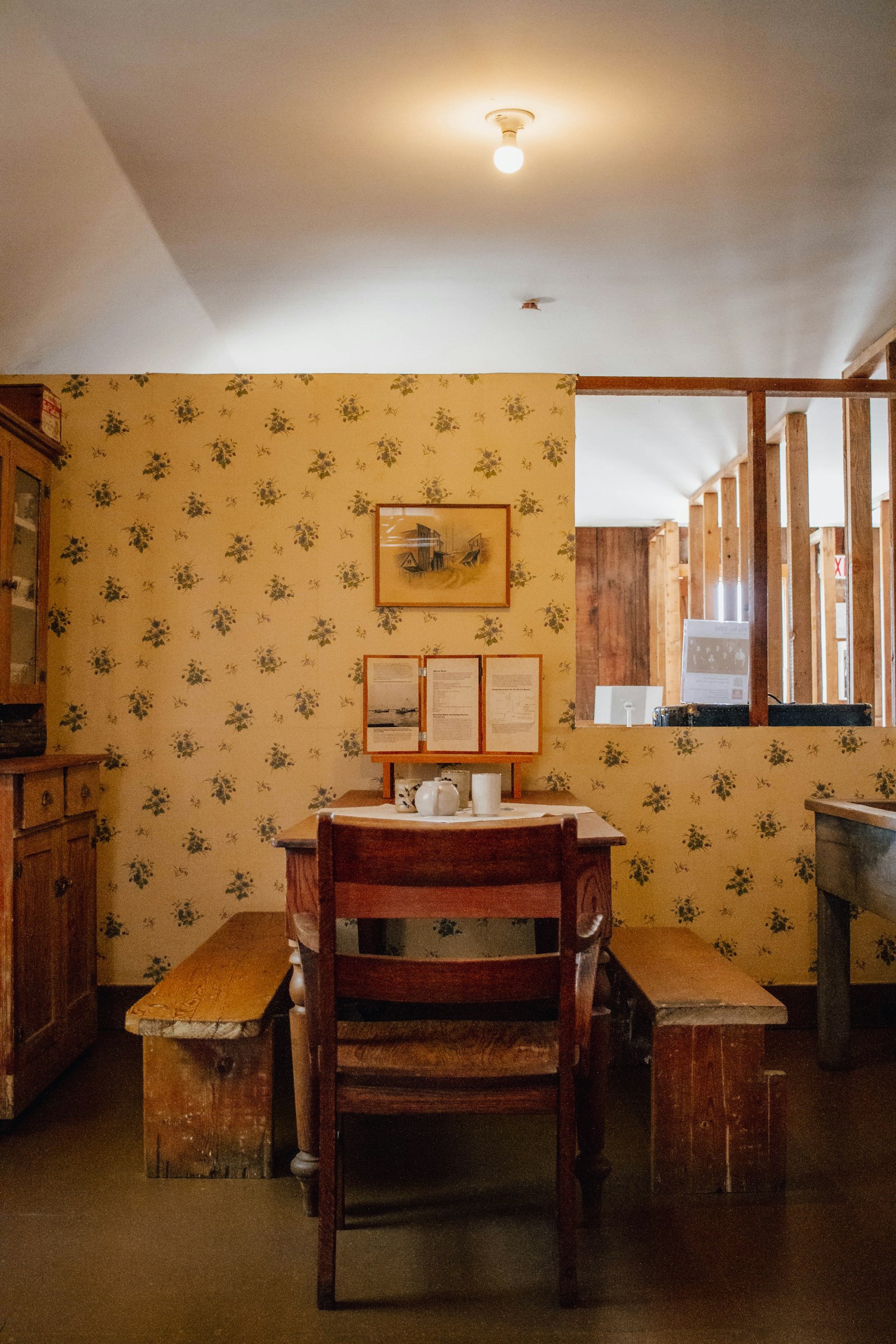 Yellow-cream sprigged floral wallpaper beside a warm-oak Windsor-back chair