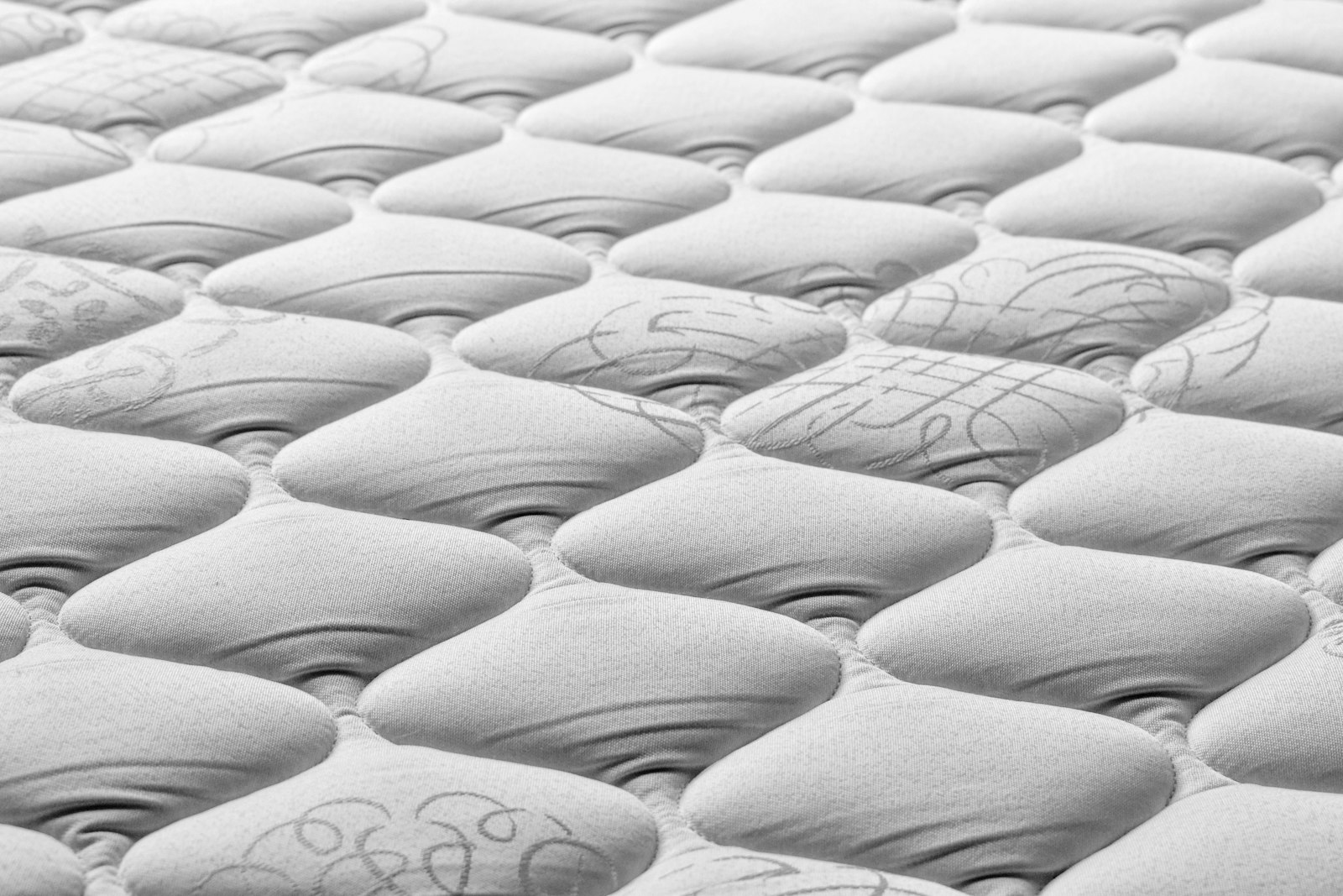 Close-up of a quilted mattress top-cover showing a tufted diamond pattern