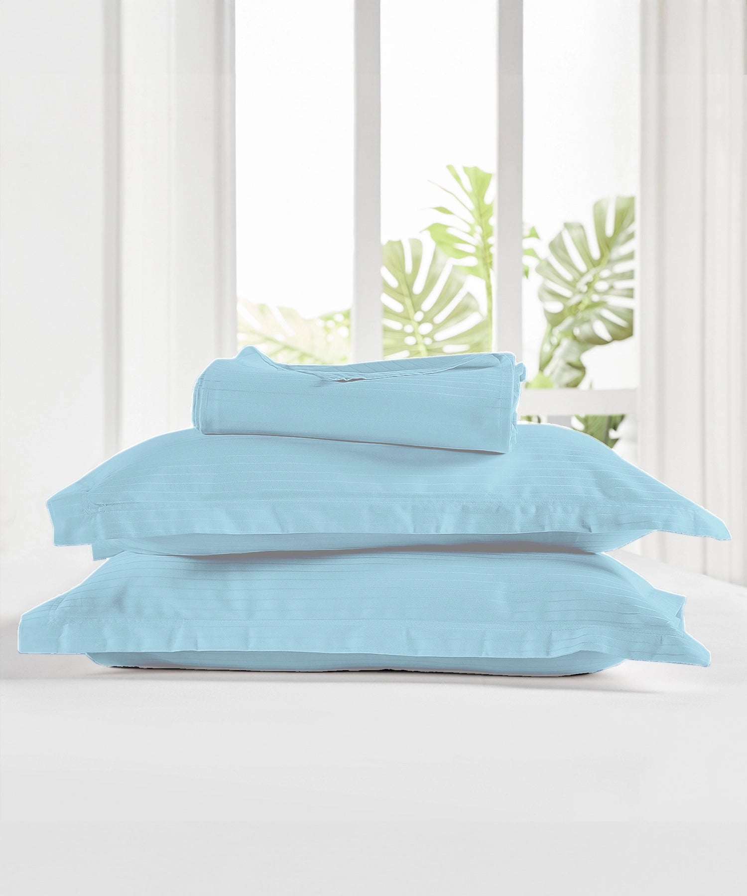 Folded stack of cotton bedsheets and pillowcases on a shelf, natural daylight